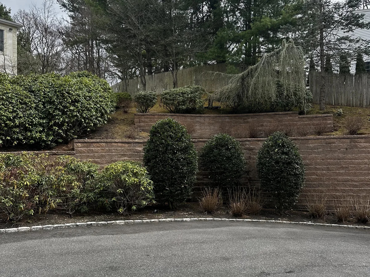 Finished landscaping with brick retaining walls and plantings at a residential property